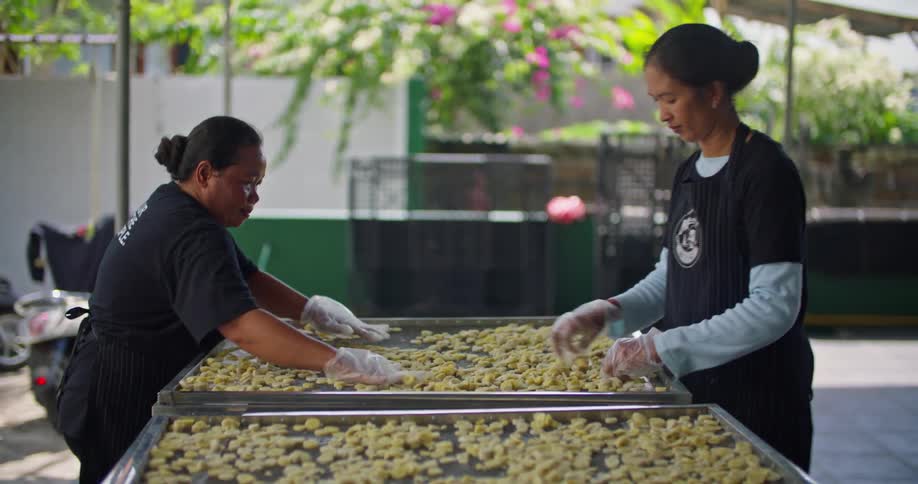 Two women separate garlic on large drying racks