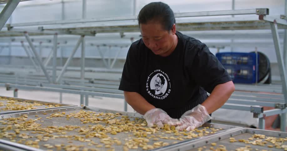 A factory worker moves garlic on large baking racks