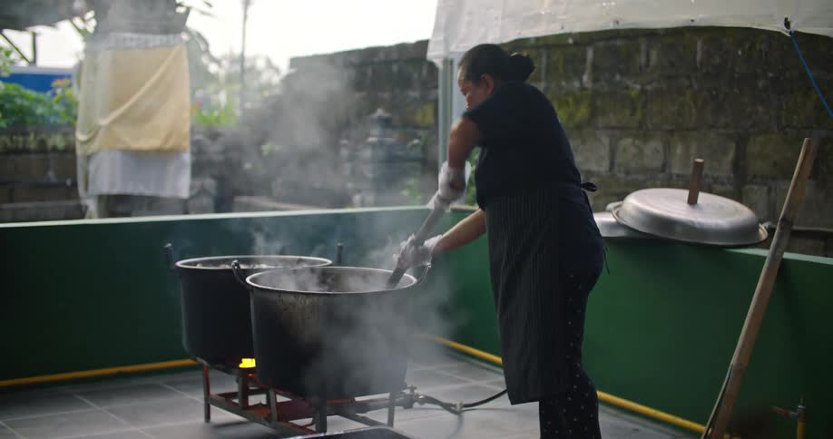 A woman is cooking seafood in a large pot in an outdoor restaurant