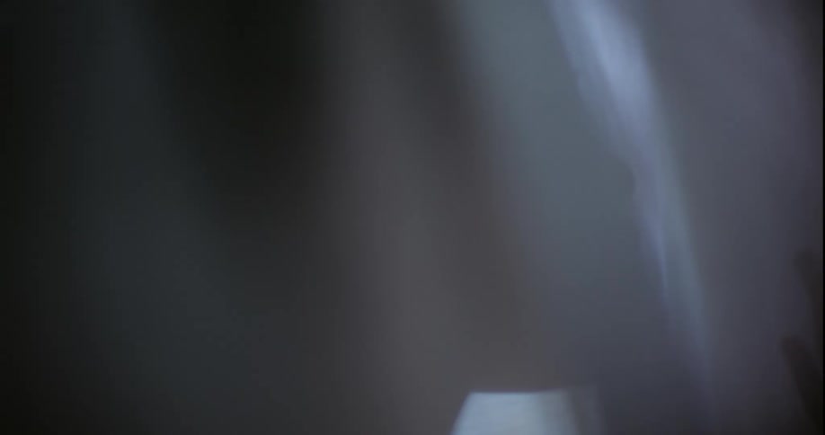 A woman is standing behind a curtain that is blowing around