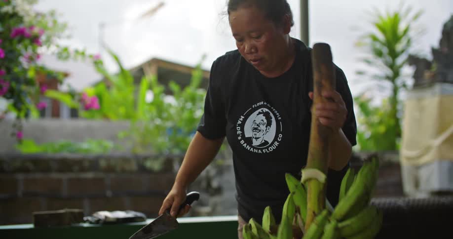 A woman is cutting bananas off the stalk