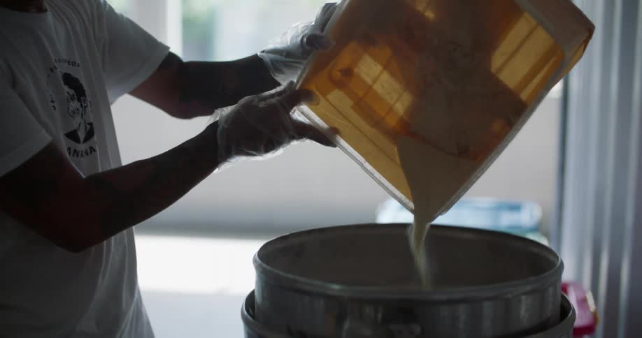A man is pouring flour into a large mixer bowl