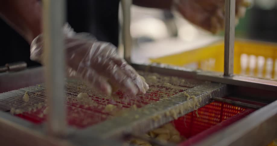 Person presses bananas through slicer into large basket