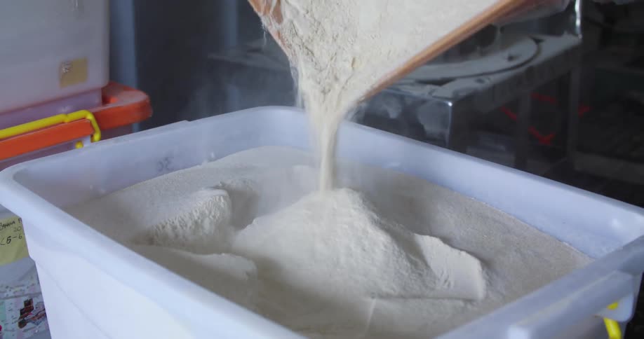 A person is slowly pouring flour from one container to another