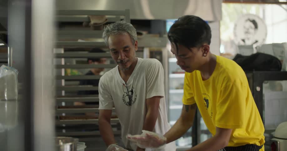 Older man instructs younger man in prepping food