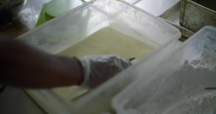 A restaurant worker scoops flour from a bin