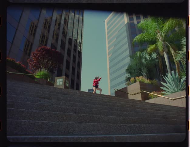 A young white woman is dancing outside around the downtown area