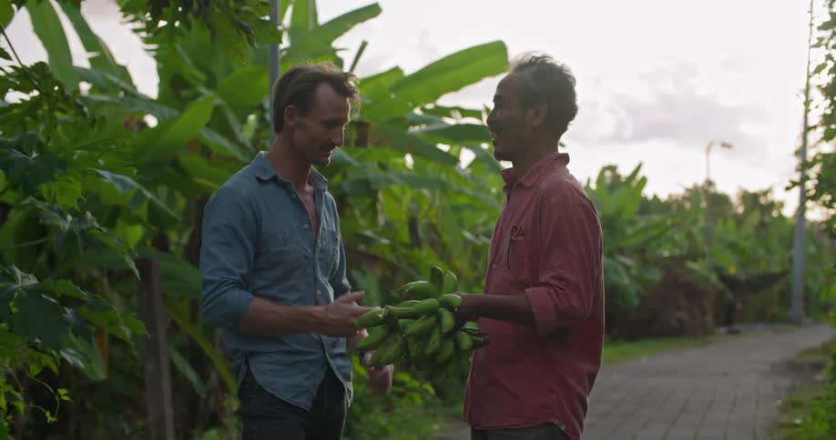 Two co workers are talking outdoors in front of the plants