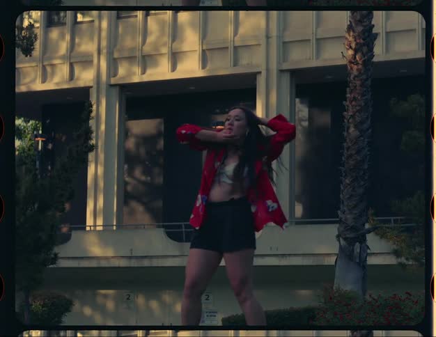 Woman dances in landscaped surrounding of building
