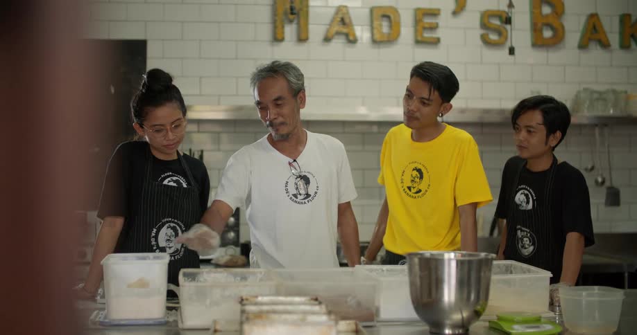 Man teaching young workers how to process food on the kitchen of a restaurant
