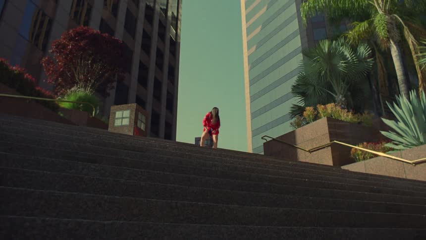 Female dancer dances at top of outdoor steps at the base of a building