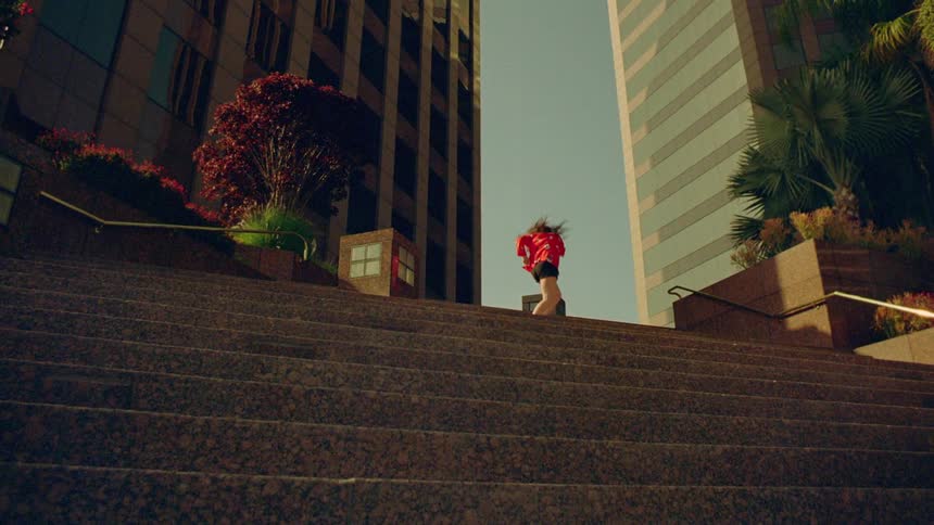 A woman is dancing outdoors in a downtown city