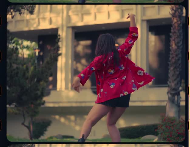 Woman dances in grass near building