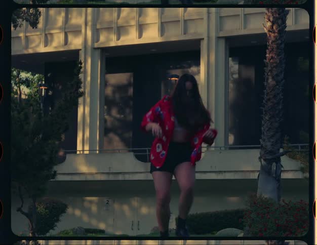 Woman dances in grass near building