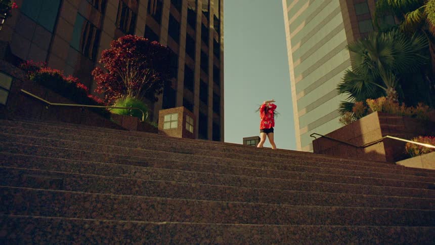 Young woman wearing a colorful jacket dancing outdoors in front of a building