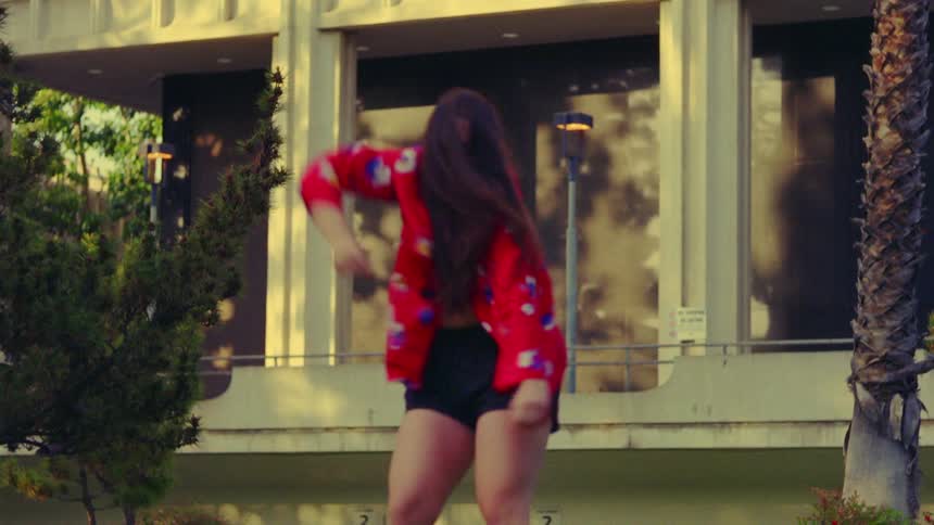 A woman dances in front of a building