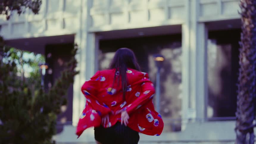 A woman is doing dance moves outside of a building
