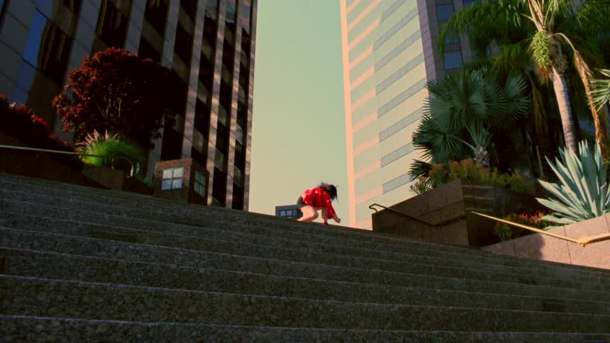 Woman dances near top of steps shadowed by skyscraper