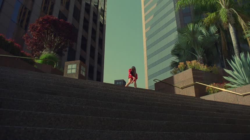A woman dances at the top of a stair case in a metropolis during the day