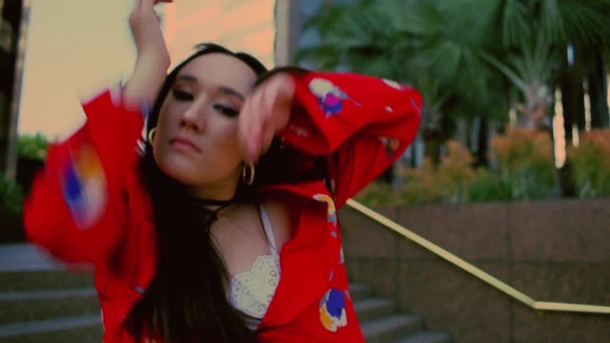 A woman is dancing outdoors in a downtown city