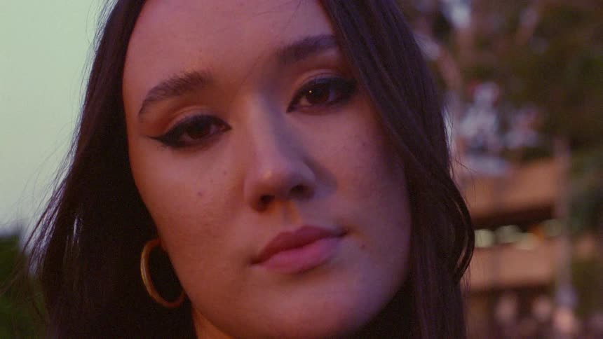 Close up of the face of a young woman standing in front of buildings in the city
