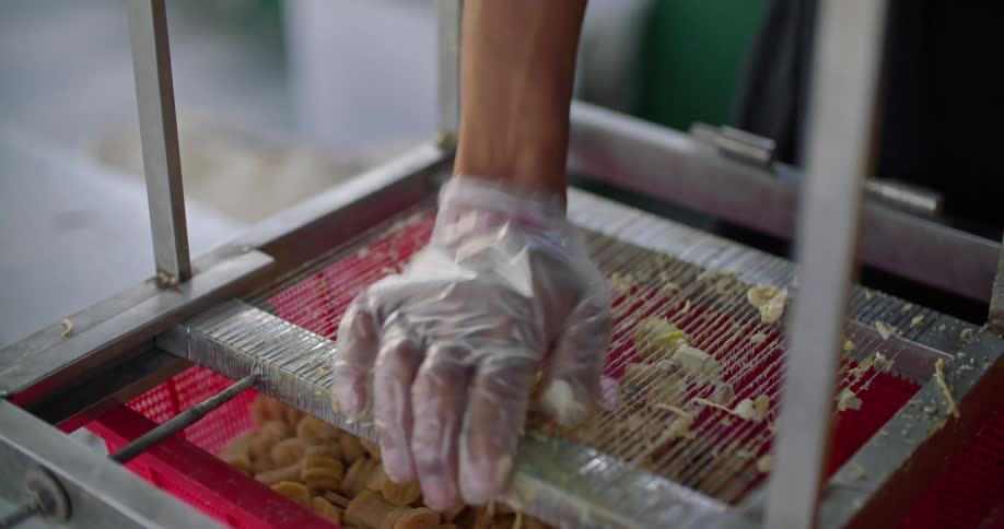 A woman slices banana by pushing it down onto a mandolin