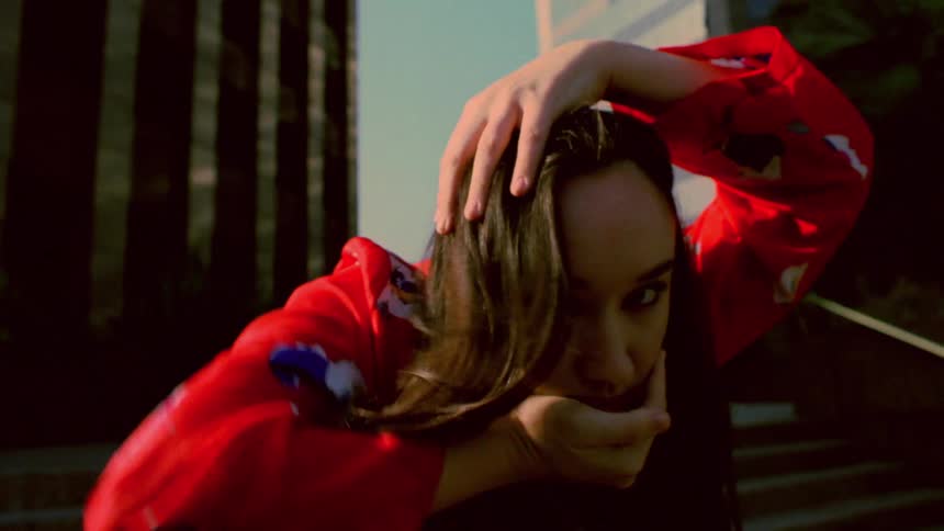 A young white woman is dancing outdoors around the downtown area
