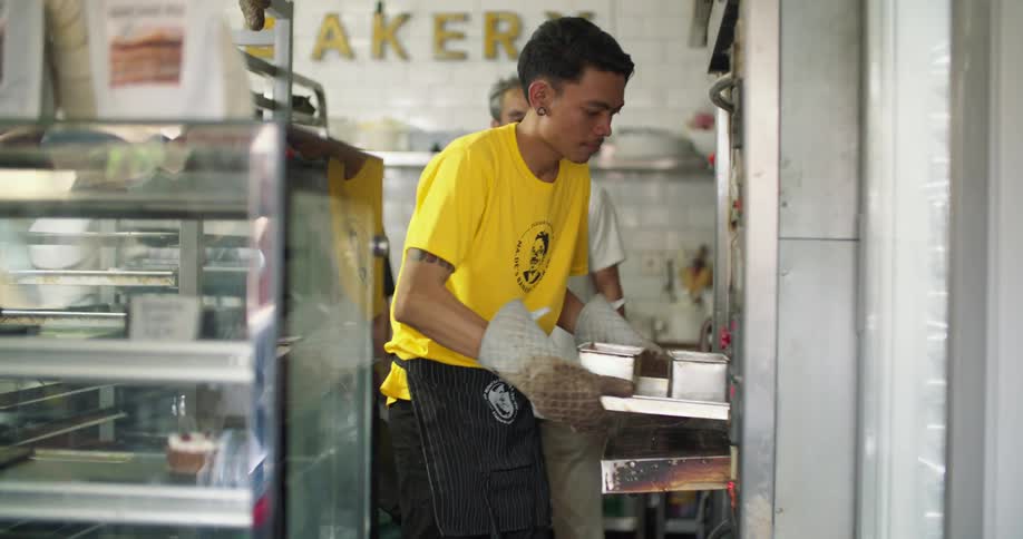 A man places a tray of food in the oven