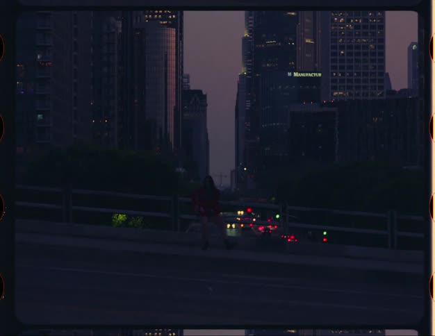 A woman dances on the walkway of an overpass in a metropolis at night