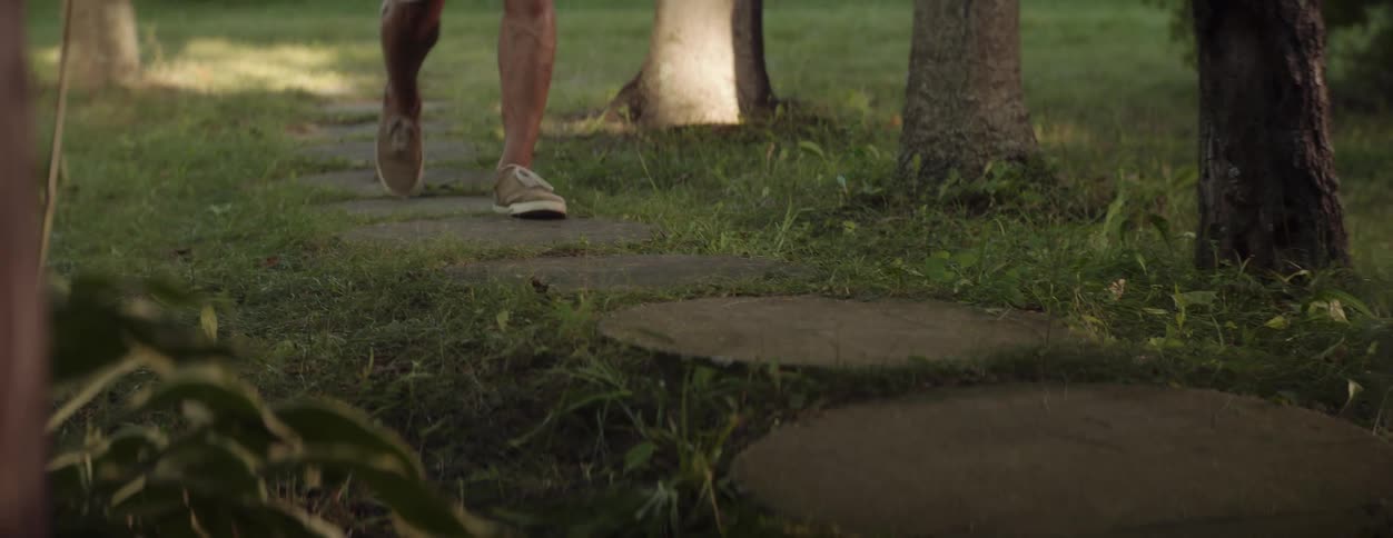 The legs and feet of two children outside and one running ahead of the other