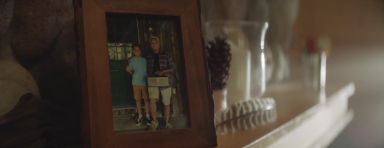 A framed photograph of a boy and his grandfather smiling and posed with fishing gear