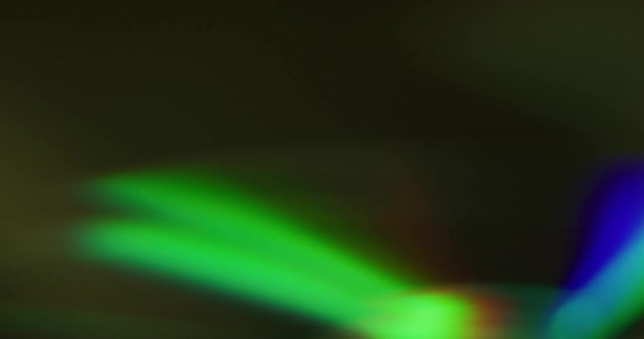 Bright light flashes across shiny iridescent surface