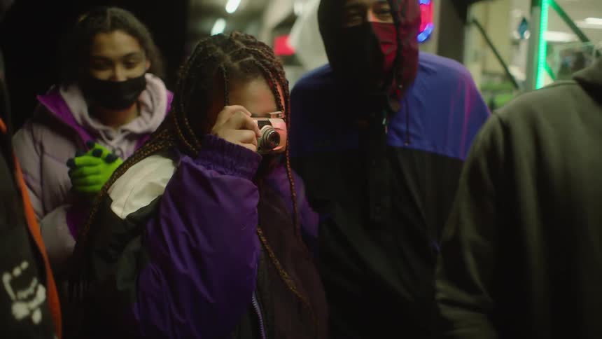 Group of people wearing face mask stand outside store smiling and one takes a picture