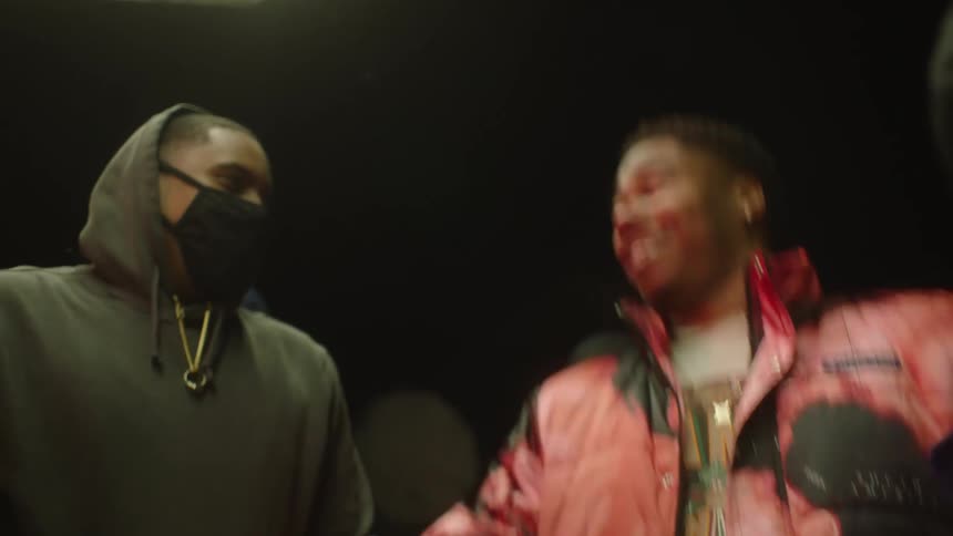 A group of friends laugh while standing outside at night