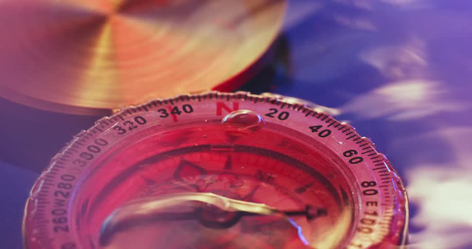 The needle on a compass spins around in a water bath