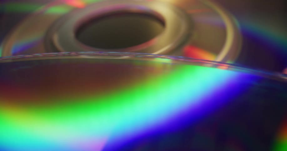 A rainbow of colors reflects and shines on the surface of compact discs