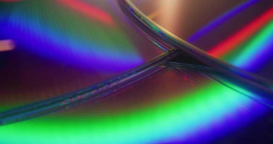 Neon lights reflect off a pile of compact discs