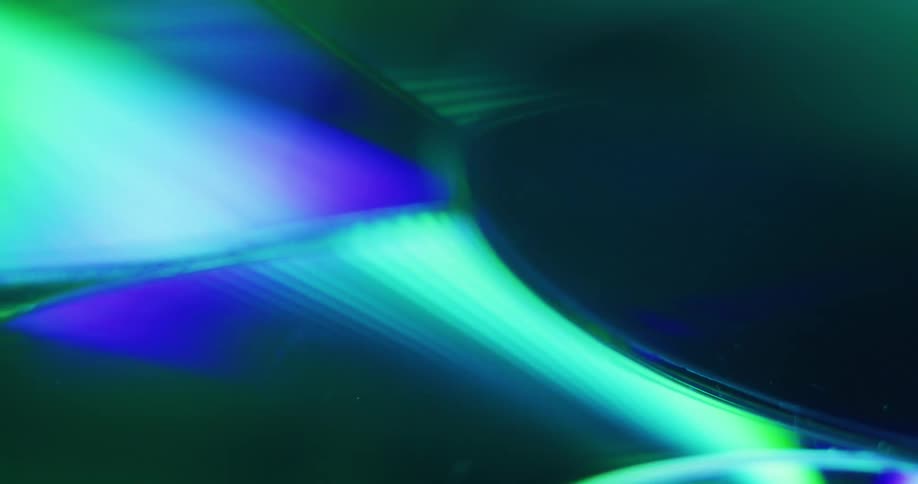 Neon lights reflect off shiny compact discs