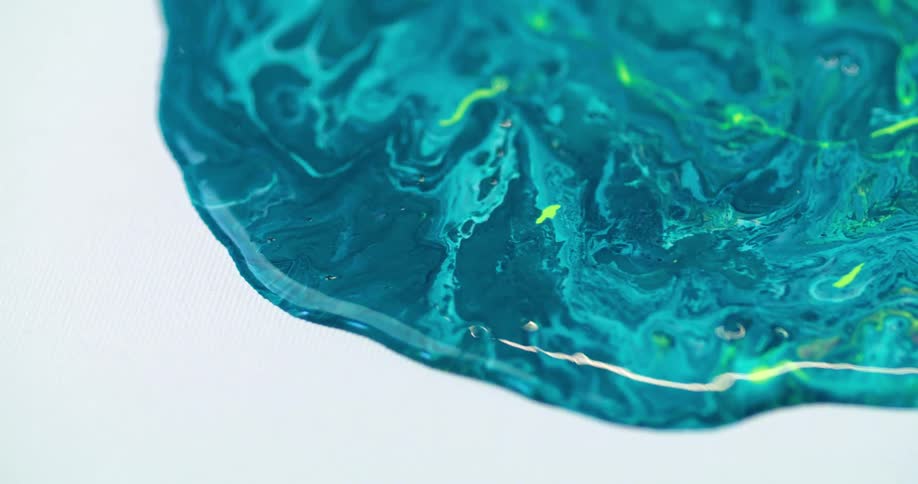 A blob of blue paint spreads and expands on a white canvas