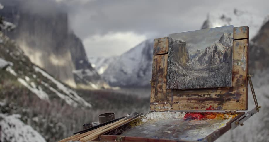 A painting of a mountain sits on a display before the mountain