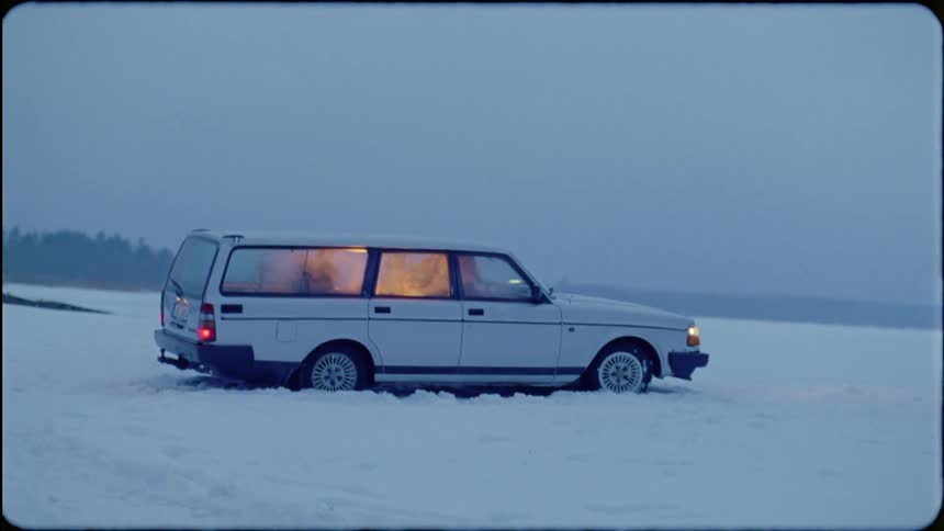 A station wagon sits parked in a snowy field