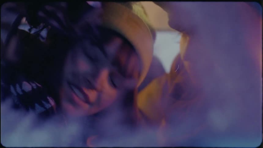 A woman wearing a knit cap is in an automobile talking to a girl and she takes off the scarf around her neck