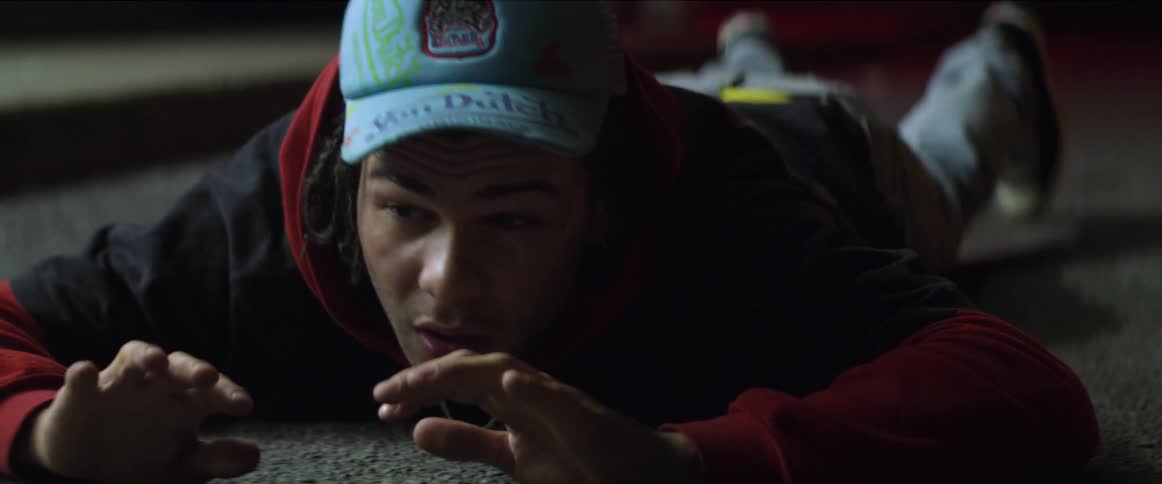 A man holds his hands up in fear while lying face down on the ground
