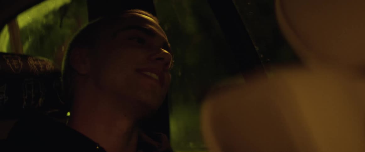 A man laughs to himself while riding in the backseat of a vehicle
