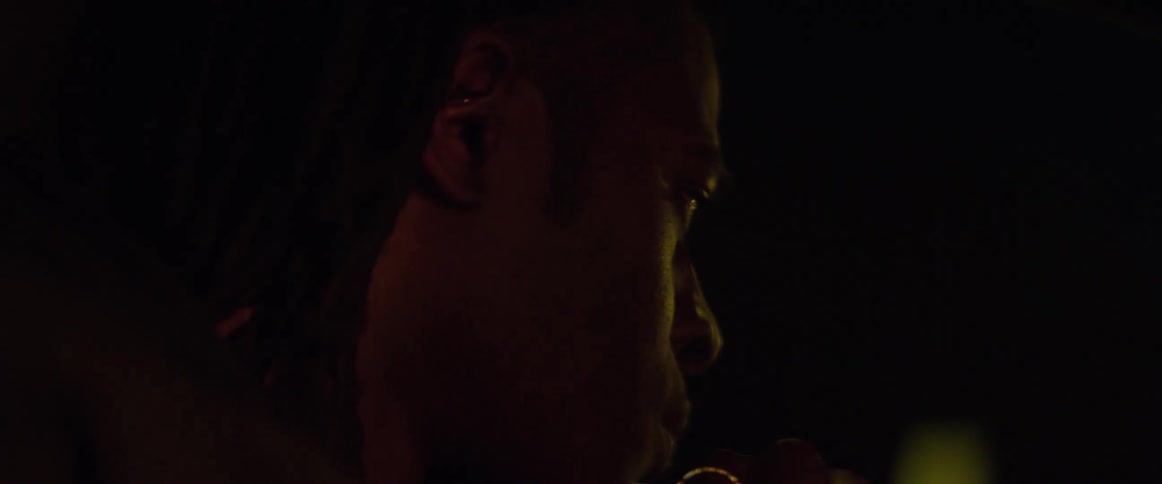 A man sits and looks out a window in to the night as he passes by bright lights