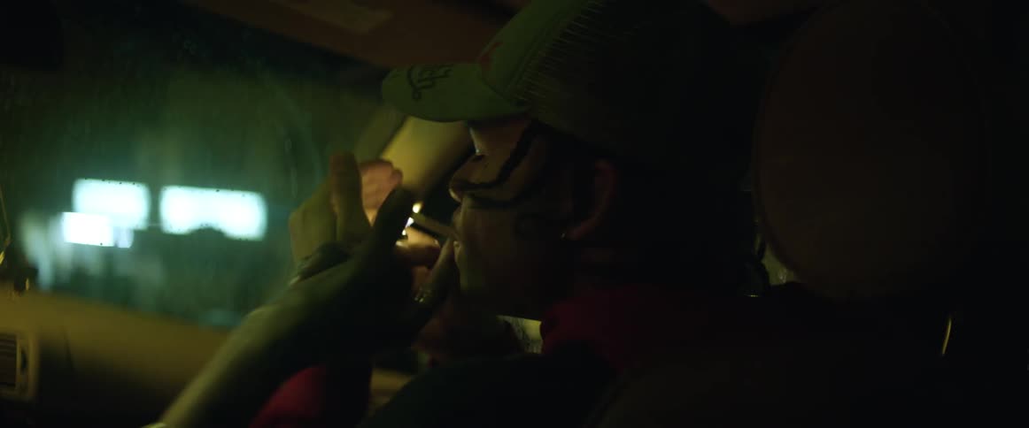 A teenager lights a cigarette while sitting the passenger seat the driver reaches and snatches it