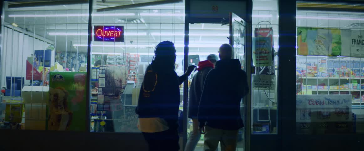 Three teenagers walk towards a store and a man comes out and bumps in to one and looks a the other who is about to light up smoke and both boys look at him apprehensively