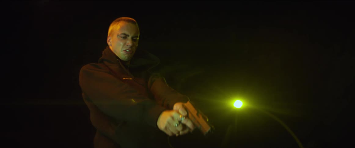A man points a handgun at the ground with his finger on the trigger