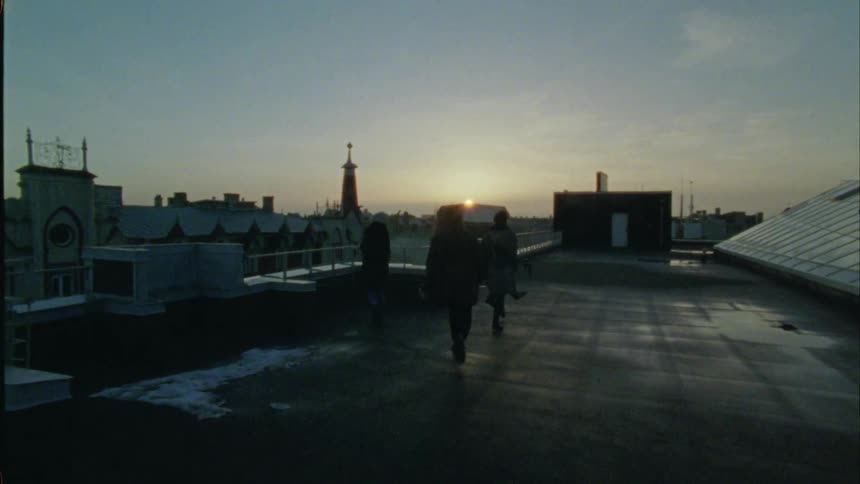 A group of friends run along a buildings rooftop
