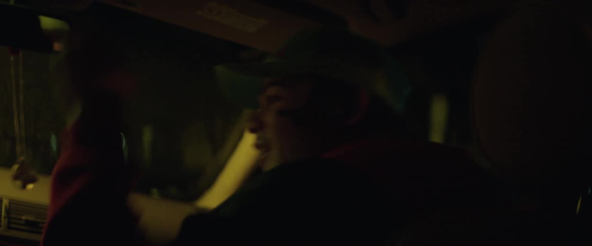 A teenage boy sitting in the passenger seat of a traveling automobile is playing around and sticking his tongue out as he laughs